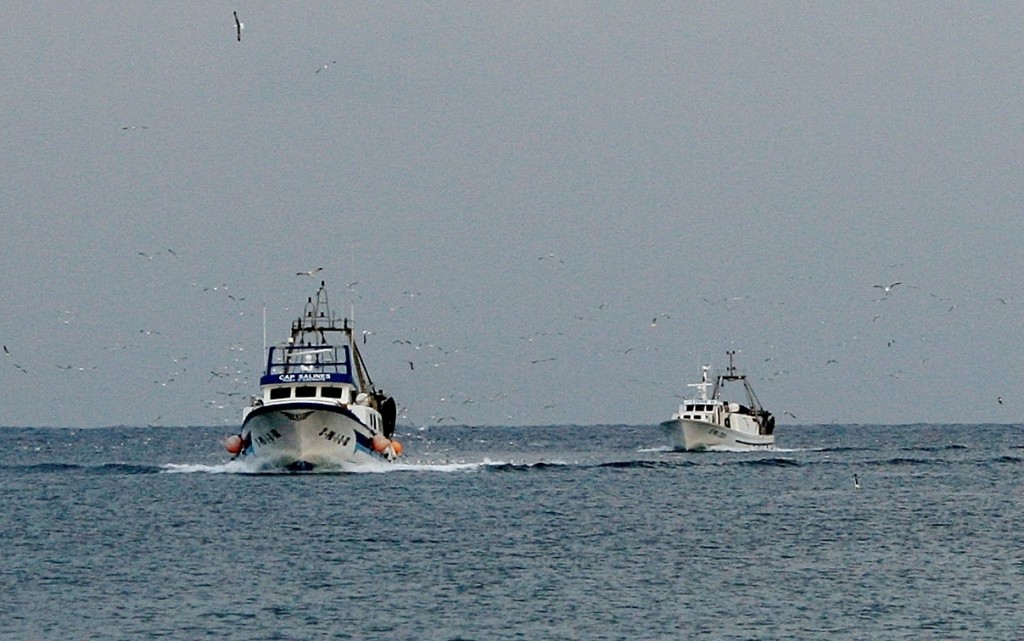 Två trålare kommer in efter dagens fiske, i bakgrunden annalkande regnväder